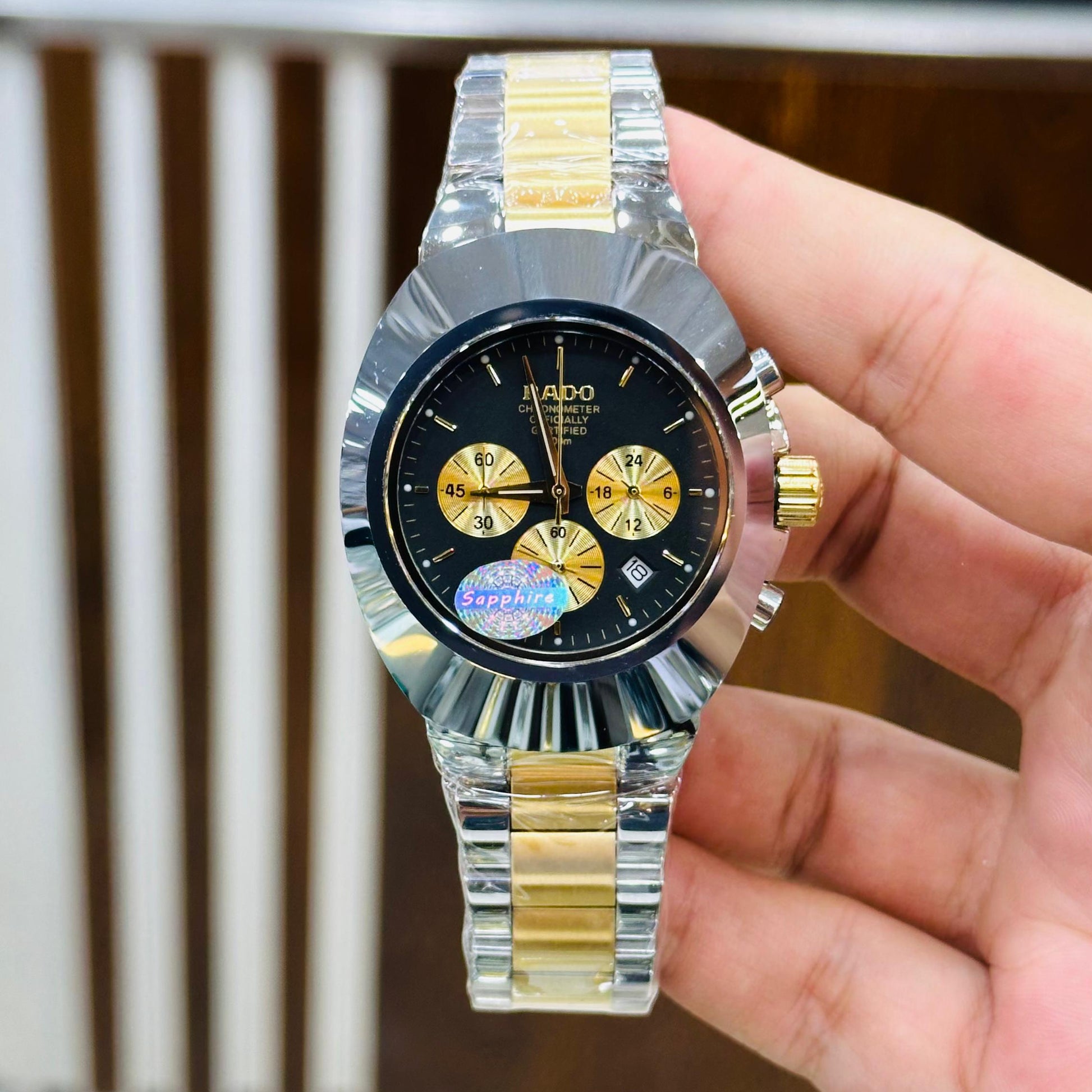 Hand holding a Rado watch with a blurred store background
