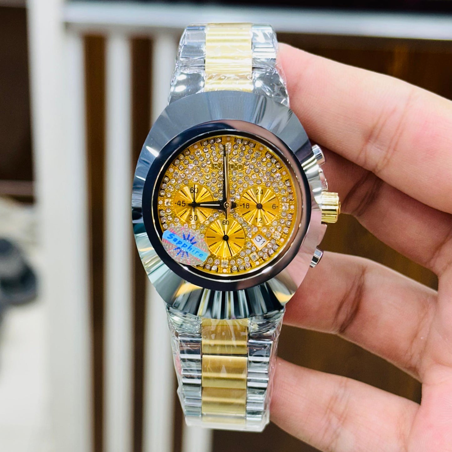 Gold and silver watch with a detailed face held by a hand against a blurred background